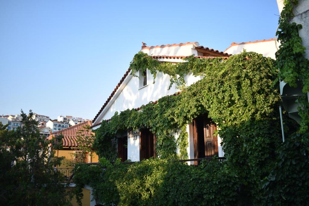 a white building covered in ivy next to a river at Pension Felippe in Pythagoreio