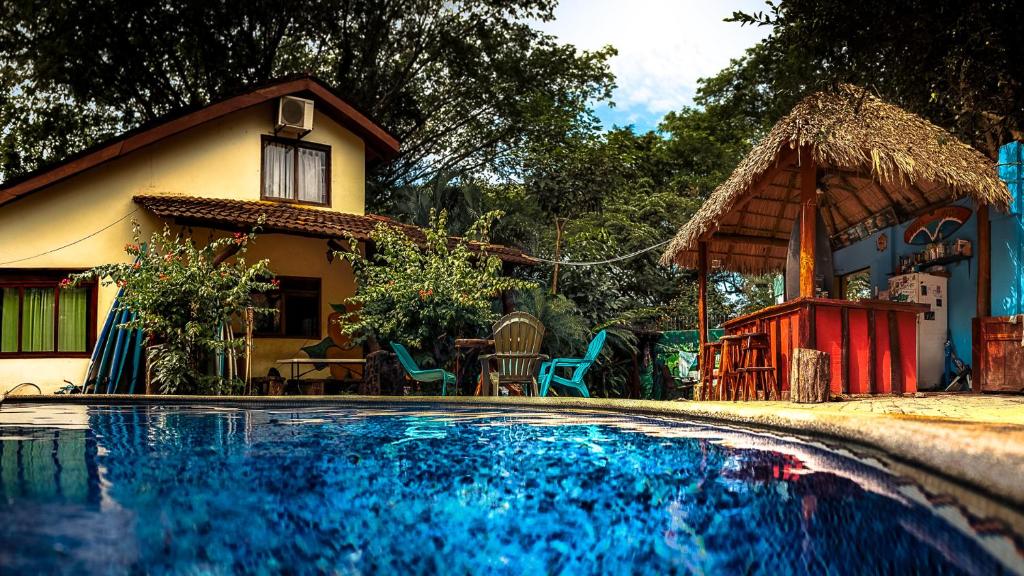 a house and a swimming pool in front of a house at Tamarindo Backpackers in Tamarindo