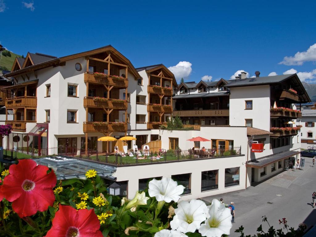 a view of a hotel with flowers in the foreground at Naturhotel Feriengut Darrehof in Serfaus