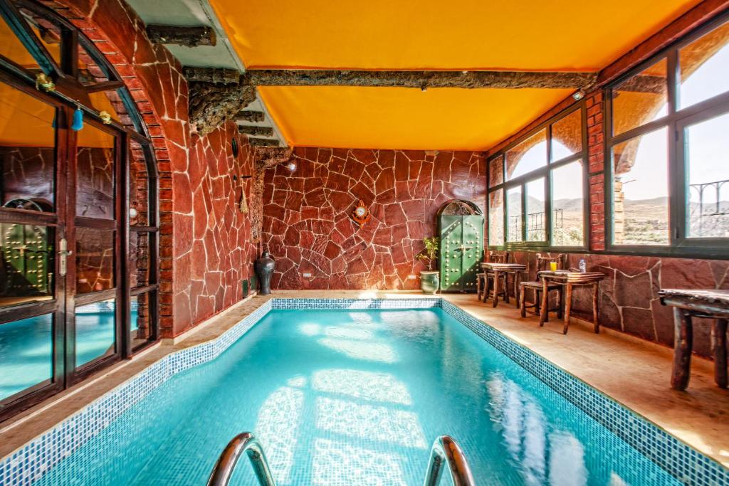 a swimming pool in a house with a brick wall and windows at Jad Auberge in Ourika