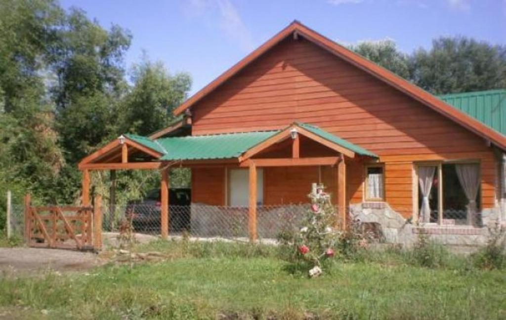 uma casa de madeira com um telhado verde em Cabaña con costa de arroyo em San Martín de los Andes