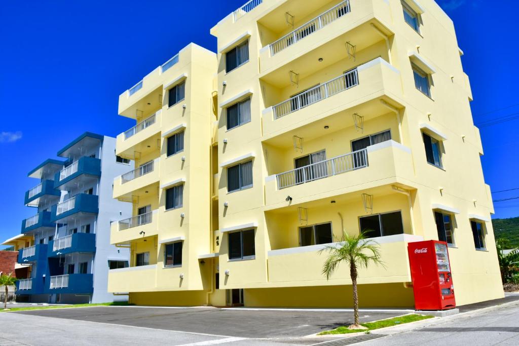 a yellow building with a palm tree in front of it at Snow ball Condominium in Kin