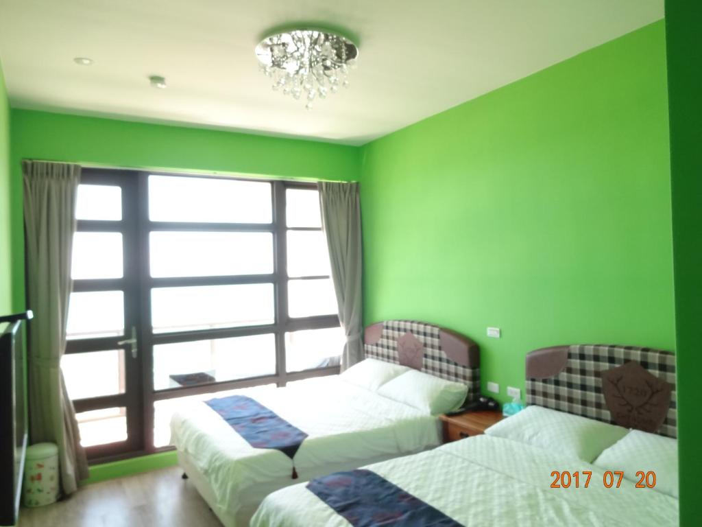 2 letti in una camera con pareti verdi e finestra di Unique Sea View B&B a Città di Hualien