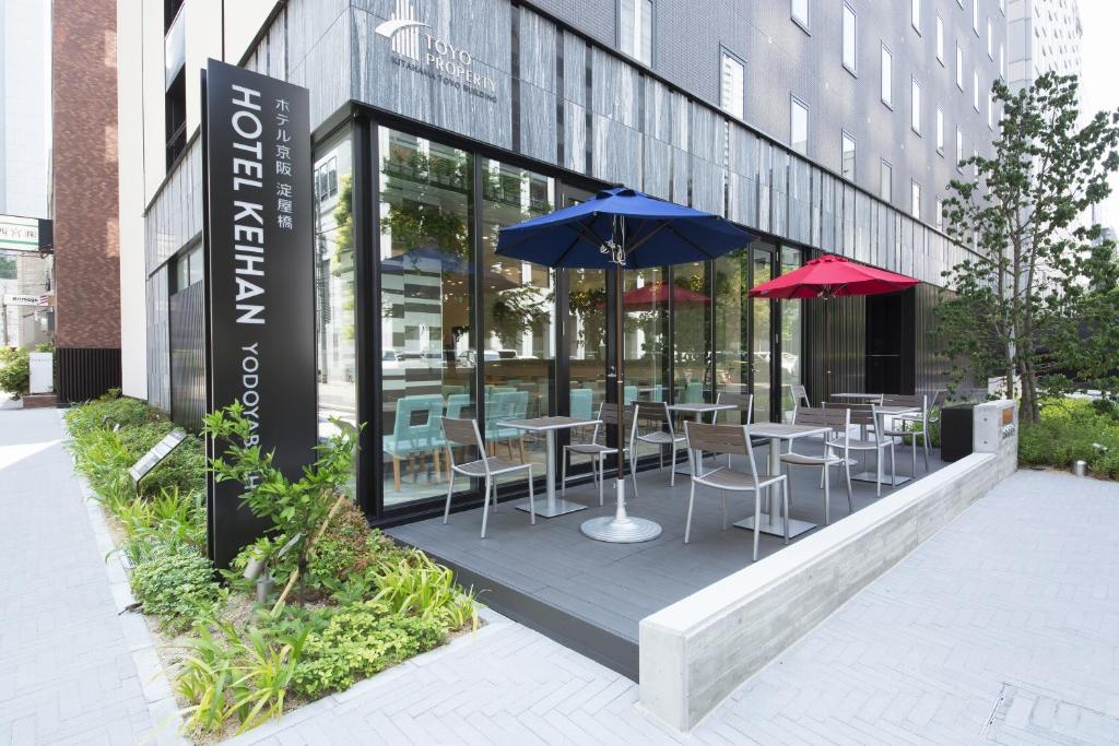 a restaurant with tables and umbrellas in front of a building at Hotel Keihan Yodoyabashi in Osaka