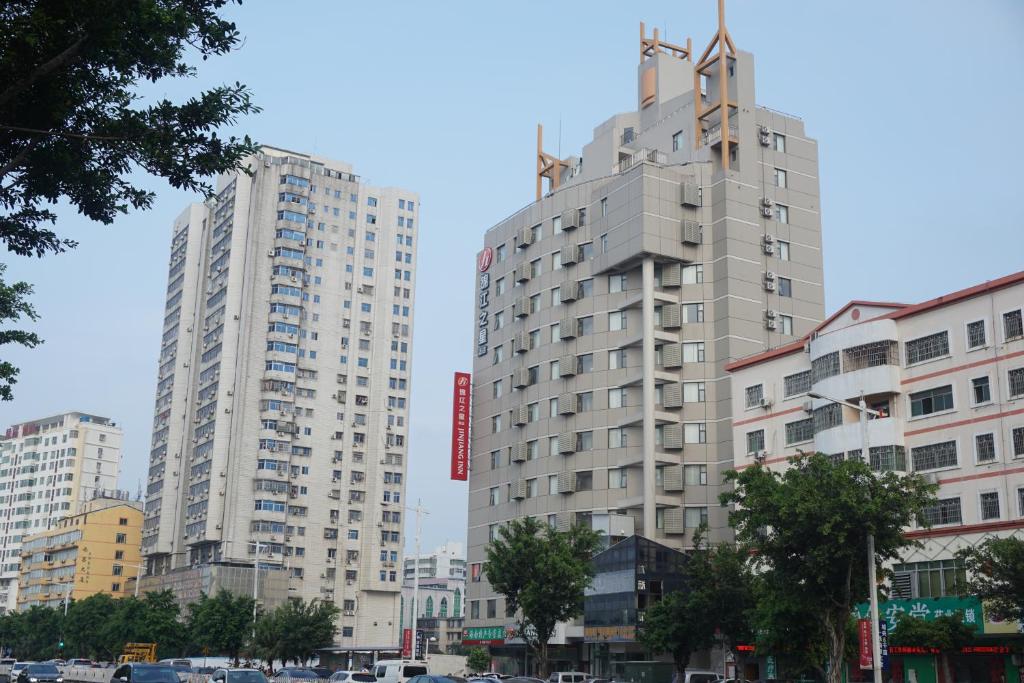 Jinjiang Inn Haikou Binhai Avenue Qilou Old Street في هايكو: مبنيان طويلان في مدينة بها سيارات