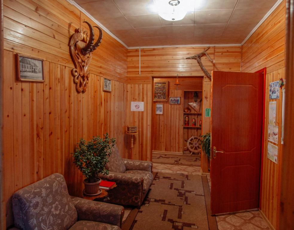 a living room with wooden walls and chairs and a door at EniRest in Karakol