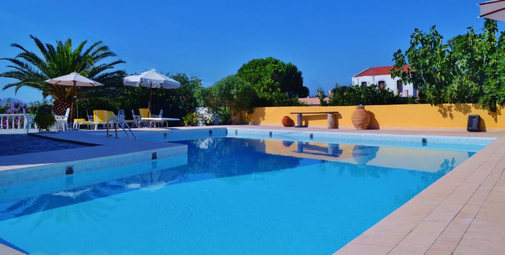 a swimming pool with chairs and umbrellas next to a building at Porfyris Hotel in Mandrákion