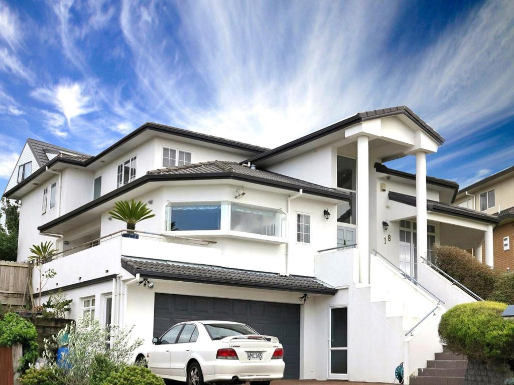 a white car parked in front of a white house at Lush & Co Auckland Bed & Breakfast in Auckland