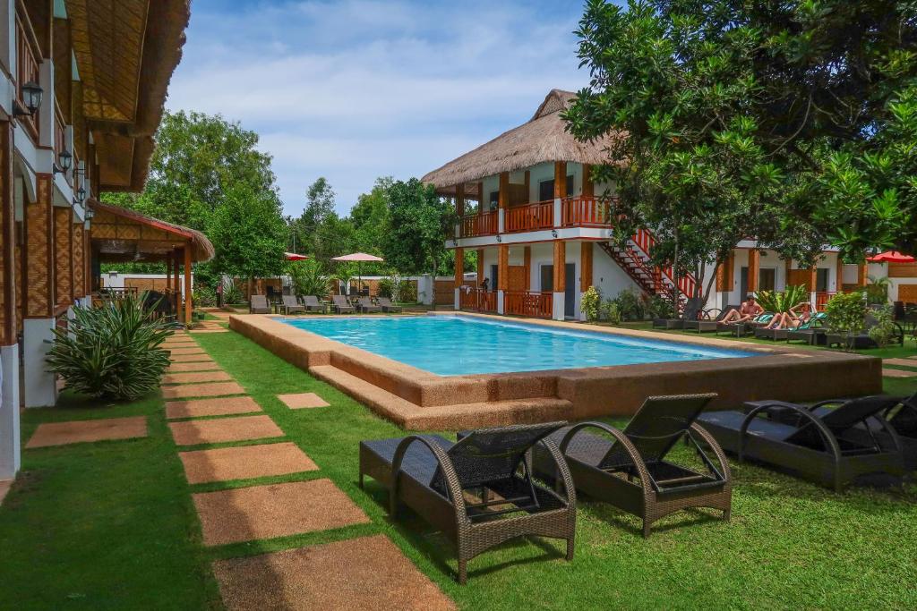 a swimming pool in a yard with chairs and a building at Scent of Green Papaya in Panglao