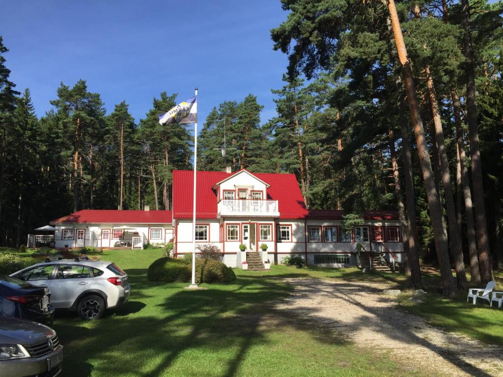 una casa con techo rojo y un coche aparcado delante en Sinisalu Apartments en Käsmu