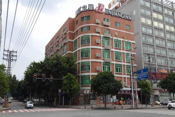 un gran edificio de ladrillo en una calle de la ciudad con un semáforo en Jinjiang Inn Dongguan Nancheng Xiping Subway Station en Dongguan