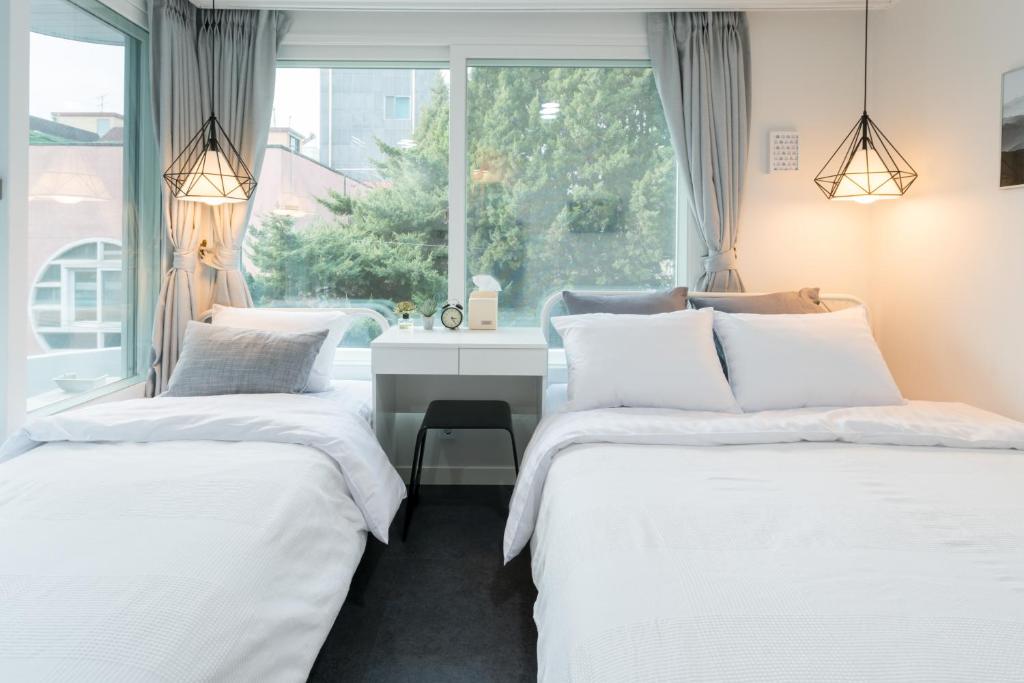 Duas camas num quarto com uma secretária e uma janela em neat house hongdae em Seul