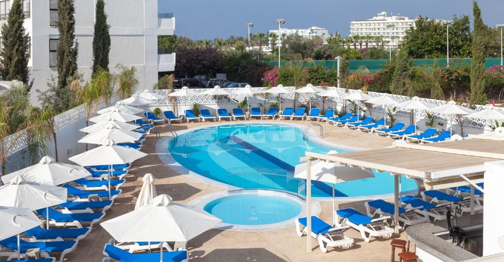 a swimming pool with chairs and umbrellas at Gaia Sun N Blue Hotel in Ayia Napa