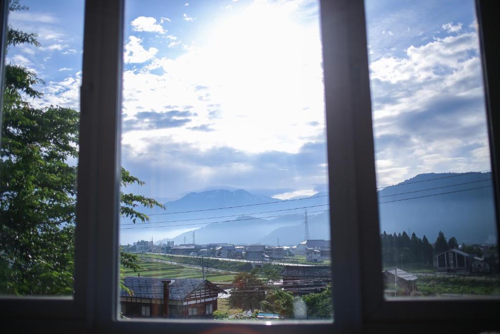 a window with a view of a field and mountains at Muikamachi Hutte in Minami Uonuma
