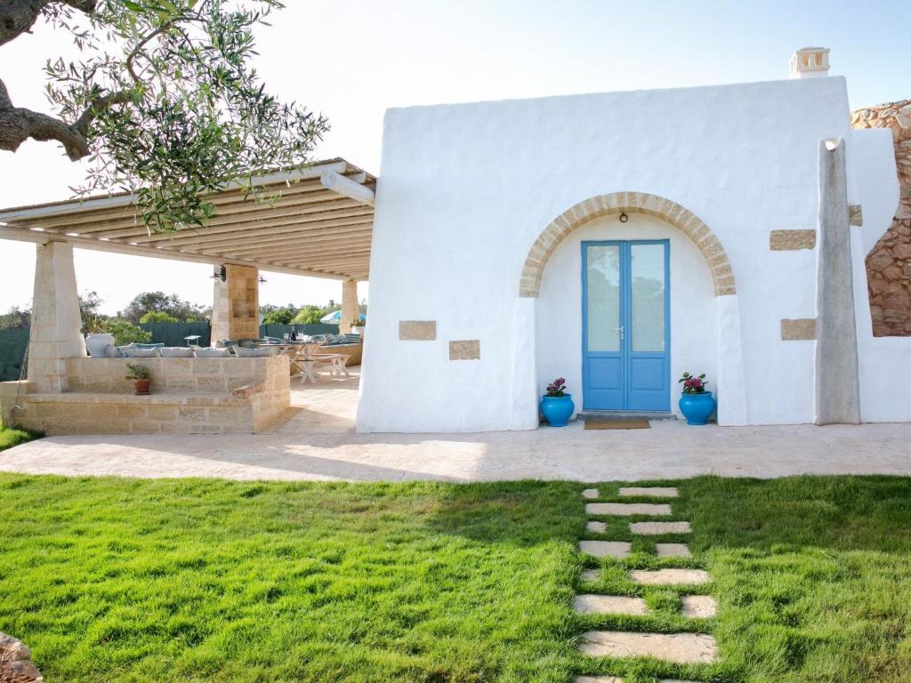 una casa bianca con una porta blu in un cortile di Luxurious Villa in Torre Suda with Jacuzzi a Torre Suda