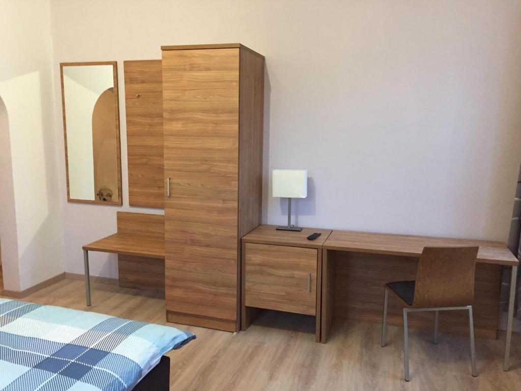 um quarto com uma secretária, uma cama e um espelho em Jujhar's Gästehaus em Wasserburg am Inn
