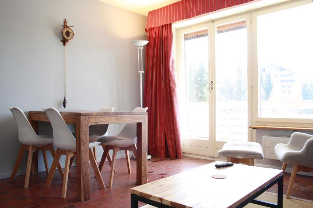 een woonkamer met een tafel en stoelen en een raam bij Cozy & Central | Palma B in Crans-Montana