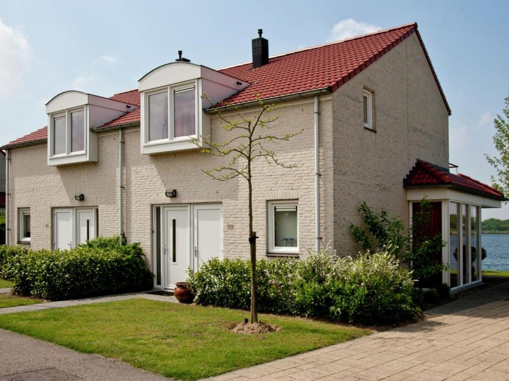 een groot huis met een rood dak bij Maaspark Boschmolenplas - Waterblik in Heel