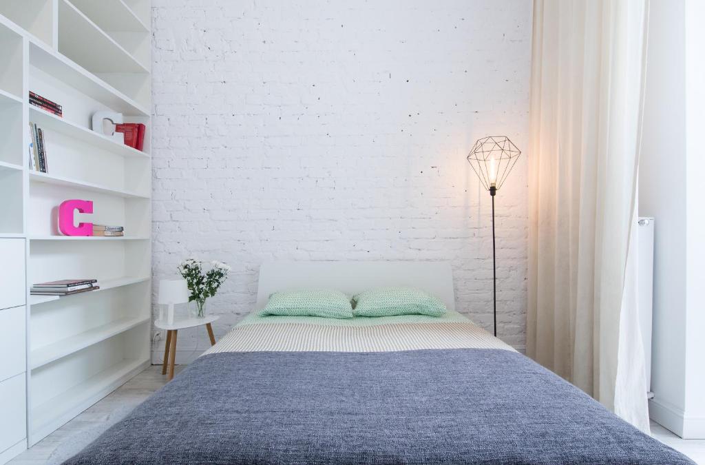 a bedroom with a bed and a white brick wall at Apartament przy OFF Piotrkowska in Łódź