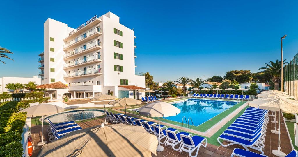 a hotel with a swimming pool with chairs and umbrellas at Globales Cala'n Blanes in Cala en Blanes