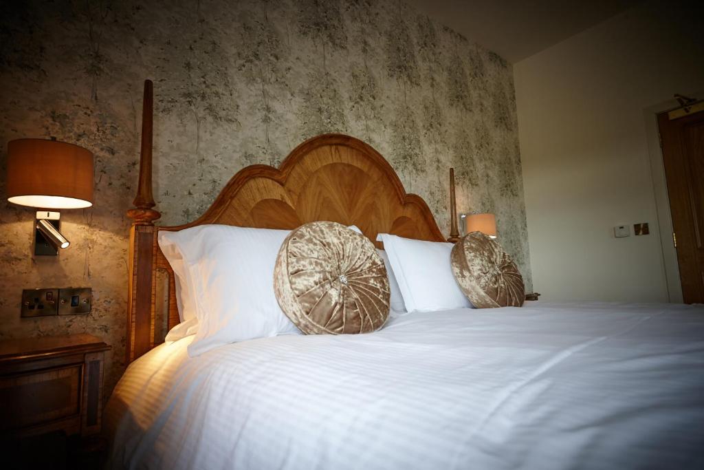 Ainstable的住宿－Heather Glen Country House，一间卧室配有一张大床和木制床头板