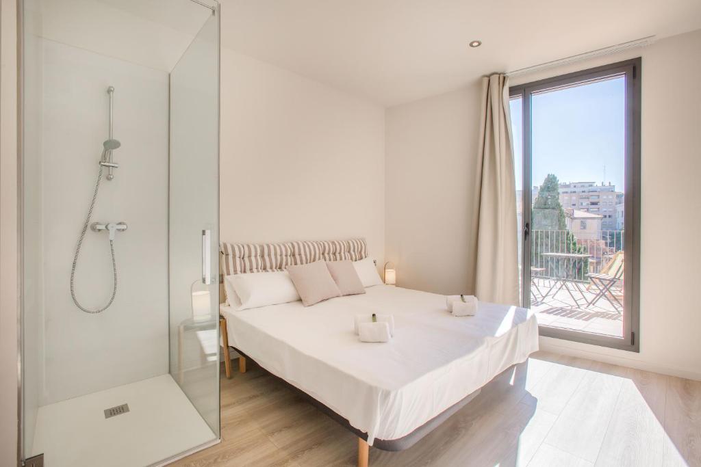 1 dormitorio con cama blanca y ducha acristalada en Flateli - Exclusivo Plaça Catalunya 4-1, en Girona