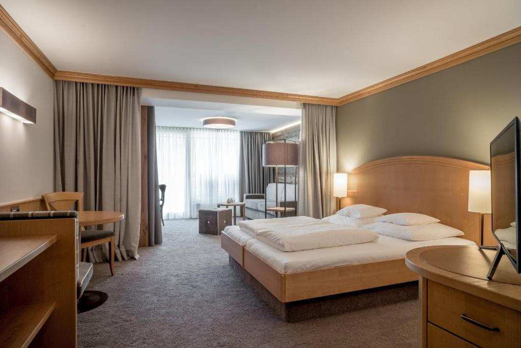 a large hotel room with a bed and a desk at Hotel Tyrolerhof in Sölden