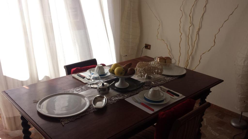 a wooden table with plates and a bowl of fruit on it at B&B Jacopino in Florence