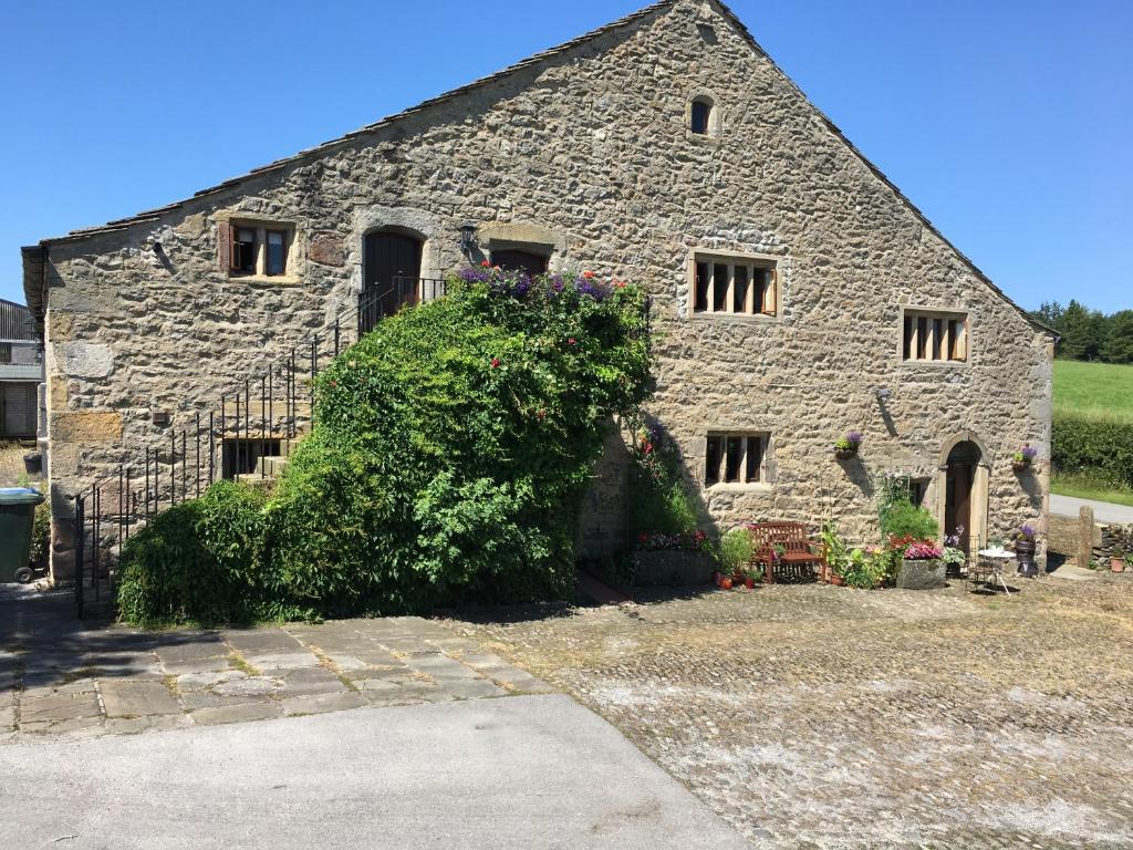 un antiguo edificio de piedra con un arbusto delante de él en Love Cottage, en Bell Busk