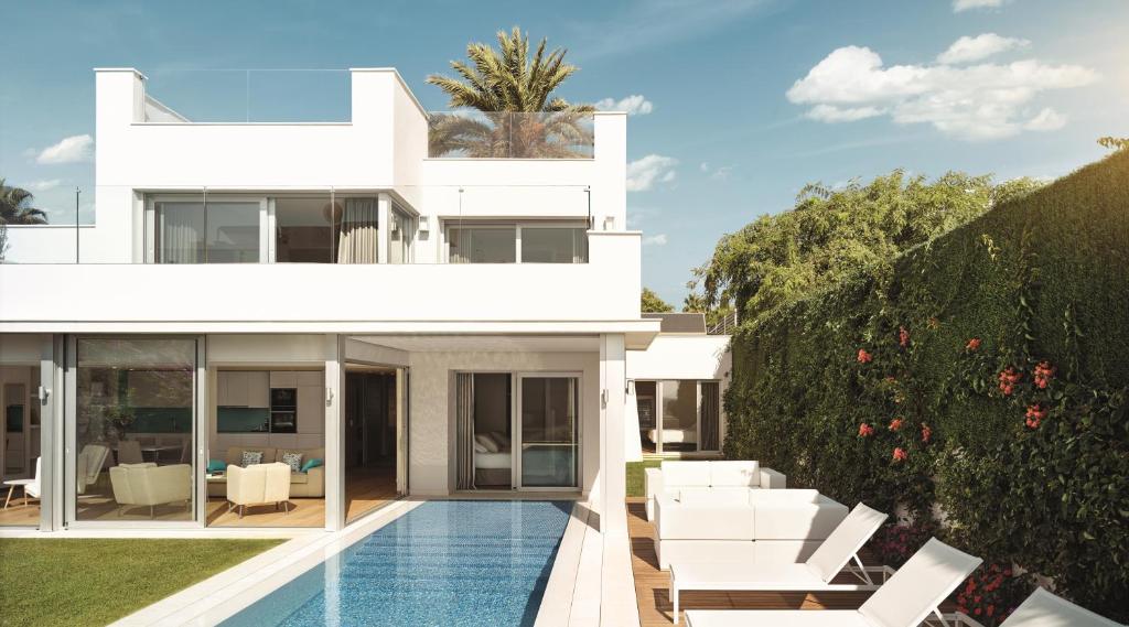 a white house with a swimming pool and white furniture at Puente Romano Marbella in Marbella