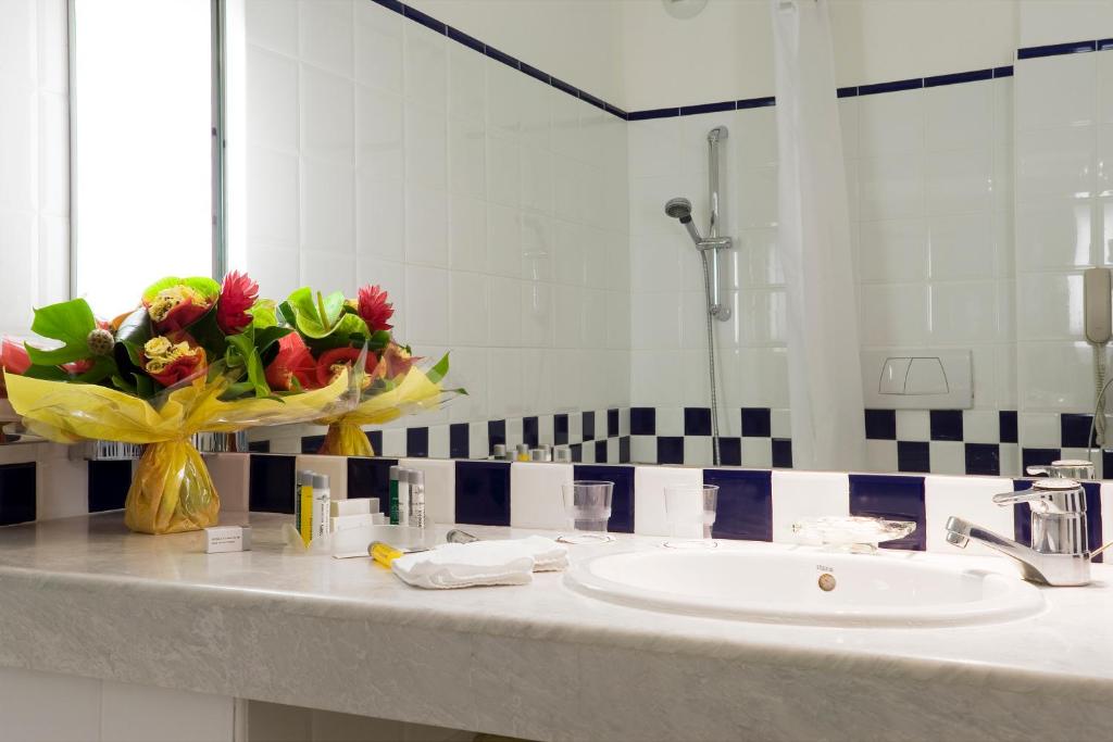 a bathroom with a sink and a vase of flowers at Hotel Cannes Montfleury in Cannes
