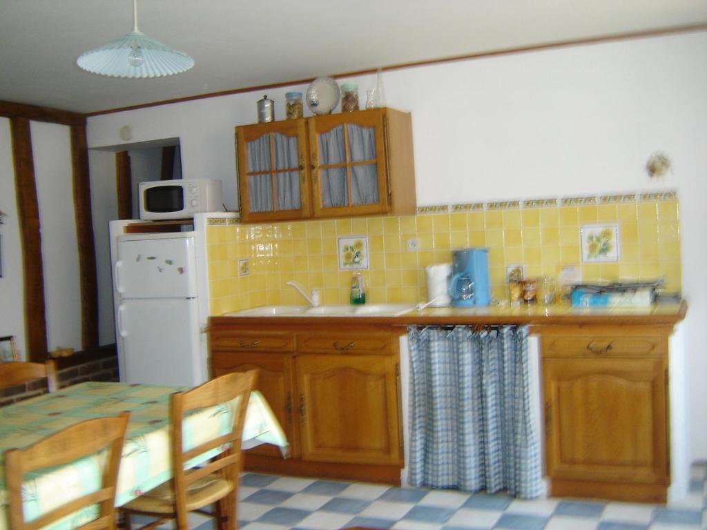 une cuisine avec un évier et une table avec des chaises dans l'établissement Les croisettes, à Campagne-lès-Boulonnais