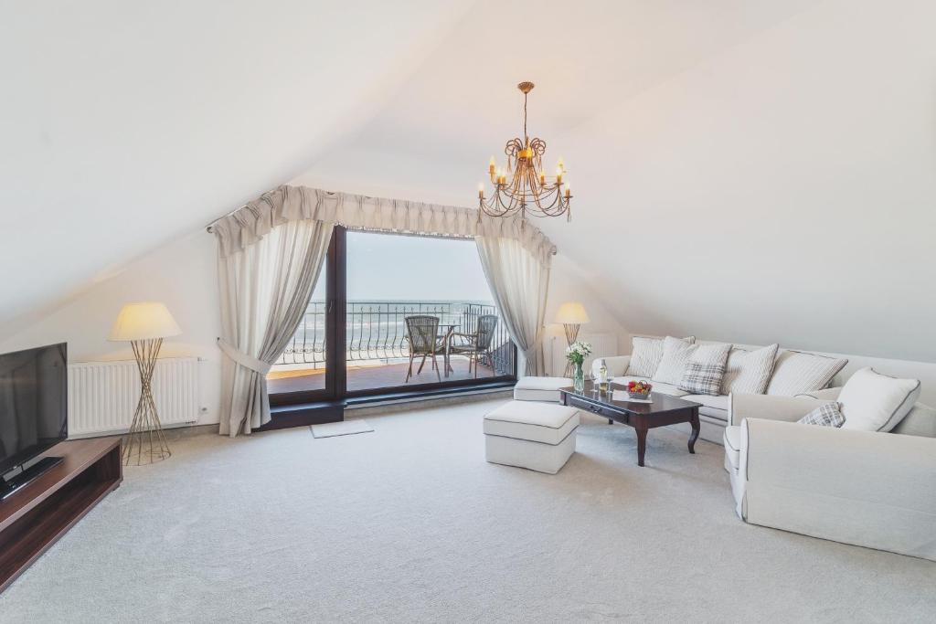 a living room with white furniture and a large window at COLUMBUS Ustka - Limanowskiego 1 in Ustka