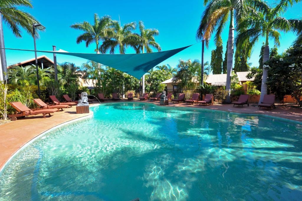 a large swimming pool with palm trees in a resort at Bali Hai Resort & Spa in Broome