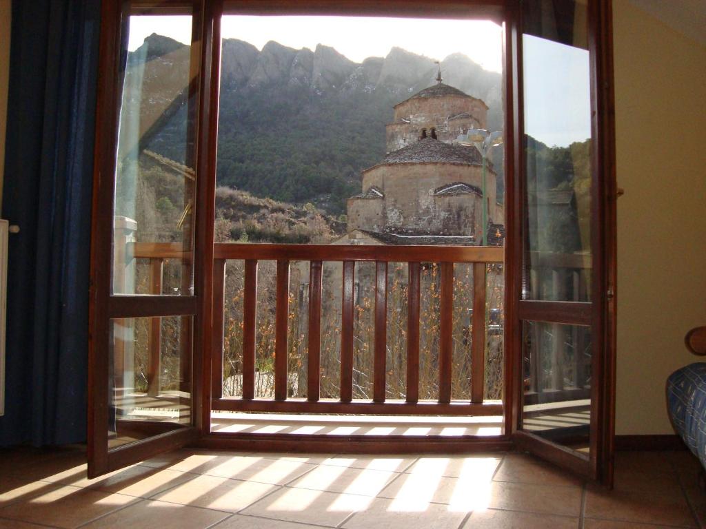 an open door to a balcony with a view of a church at apartamentos turisticos san juan de la peña in Santa Cruz de la Serós