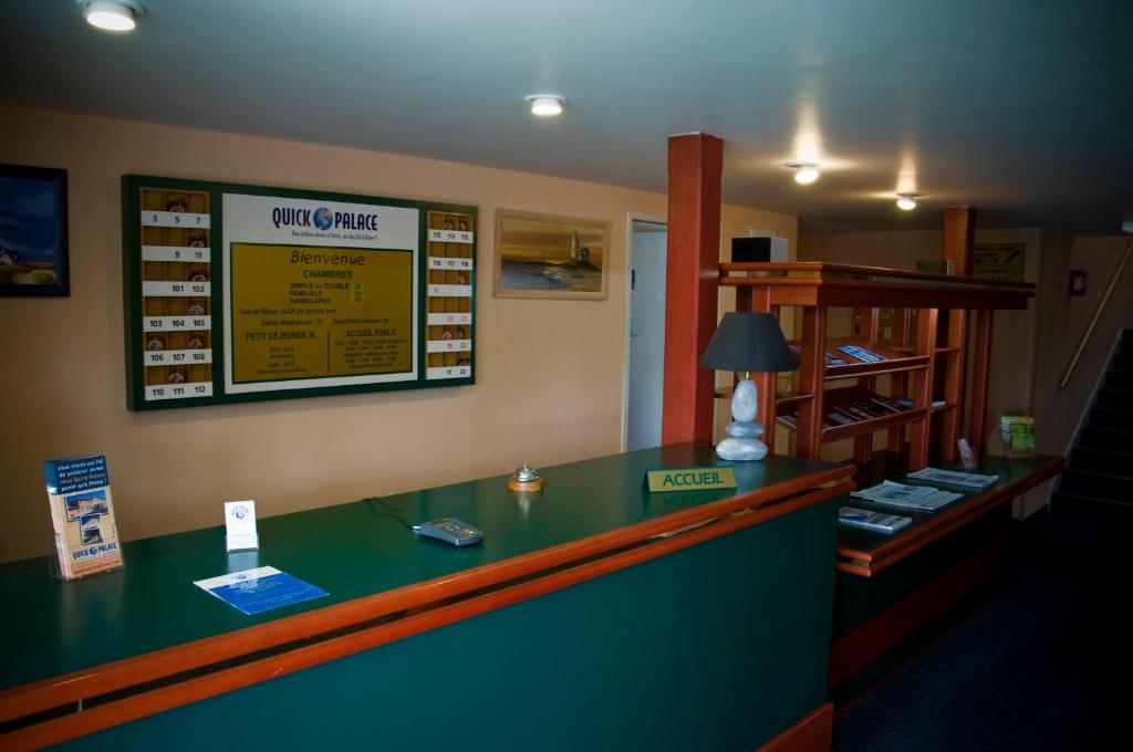 un comptoir de caisse dans un restaurant avec un panneau sur le mur dans l'établissement Quick Palace Vannes, à Vannes