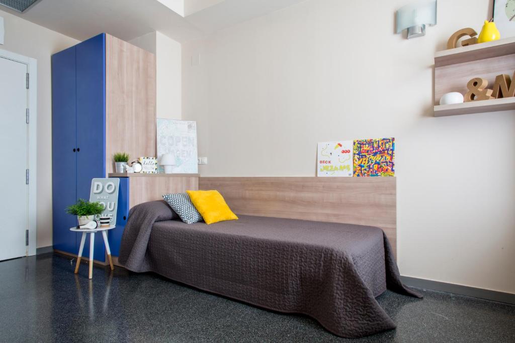 a bedroom with a bed with a yellow pillow on it at Residencia Universitaria Damia Bonet in Valencia