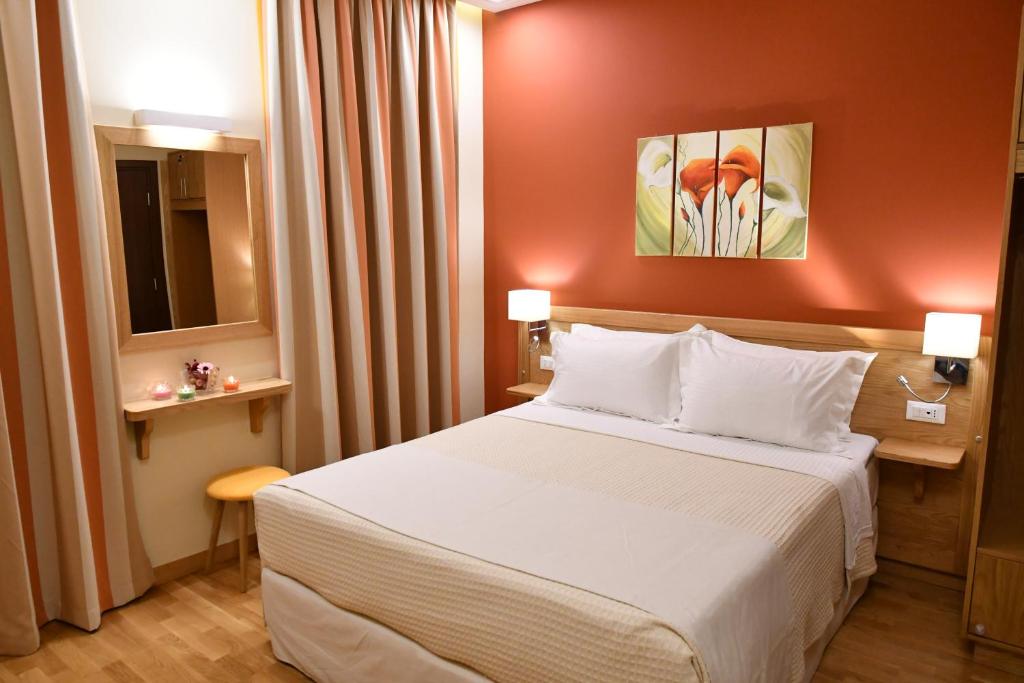 um quarto de hotel com uma cama e uma parede vermelha em Onar Pension em Nafplio