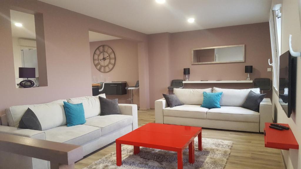 a living room with two white couches and a red table at La Villa Geiss in Épernay