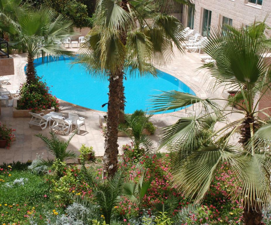 a large swimming pool with palm trees and plants at Petra Palace Hotel in Wadi Musa