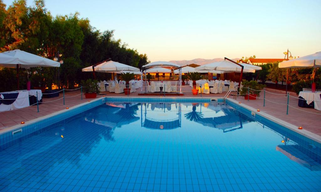 a large swimming pool with tables and umbrellas at Agriturismo Arabesque in Balestrate