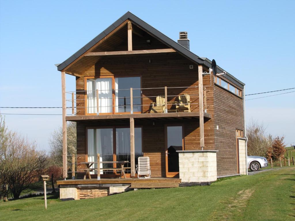 a wooden house with a balcony on a grass field at Allongueroye in Houffalize