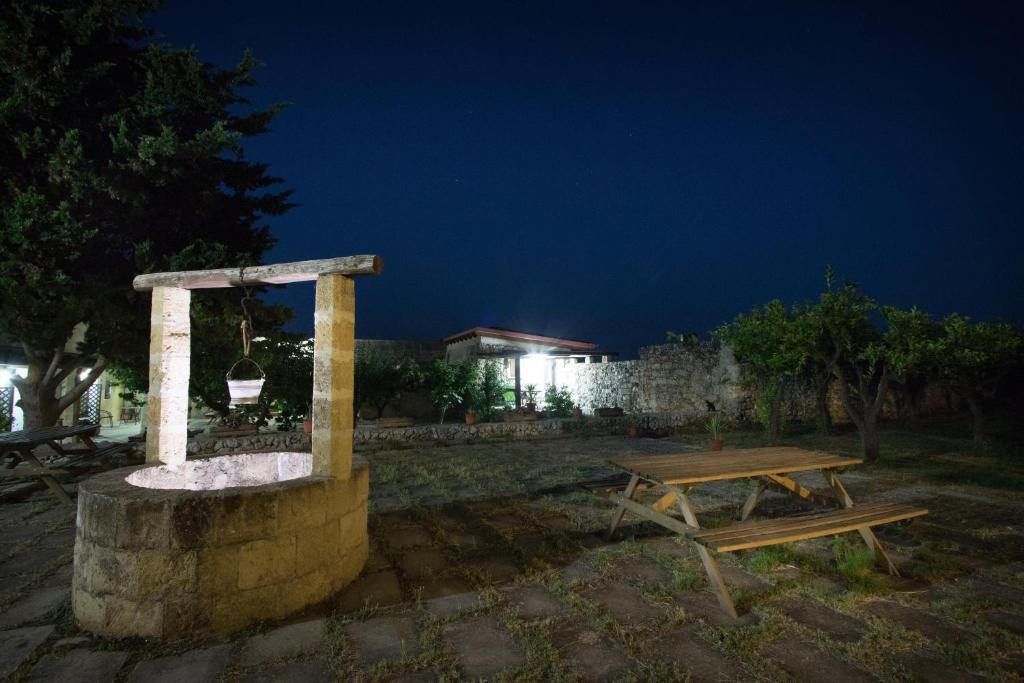 uma mesa de piquenique e uma fonte de pedra à noite em Bio-Agriturismo masseria La Palombara em Salve