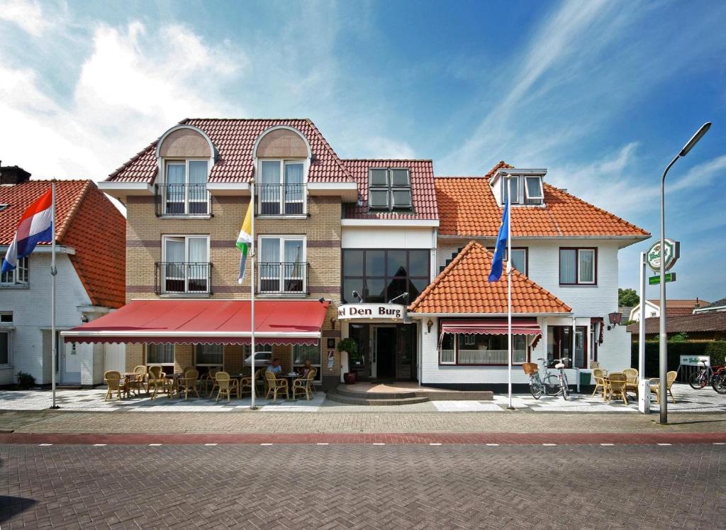 een gebouw op een straat met vlaggen en tafels bij Hotel Brasserie Den Burg in Den Burg
