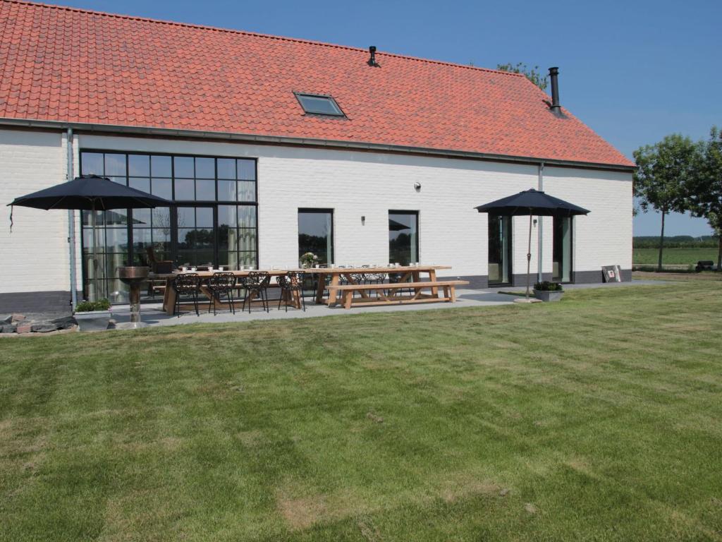 a building with tables and umbrellas in a yard at Elegant Farmhouse in Zuidzande with Private Garden in Zuidzande