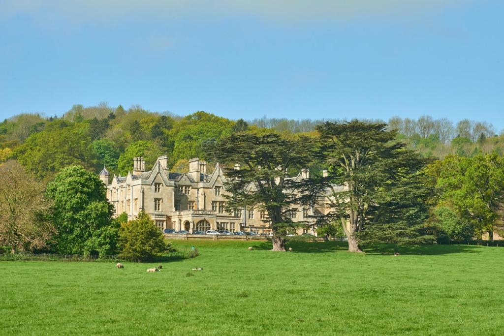 a large house in a field with sheep in the grass at Dumbleton Hall Hotel in Broadway