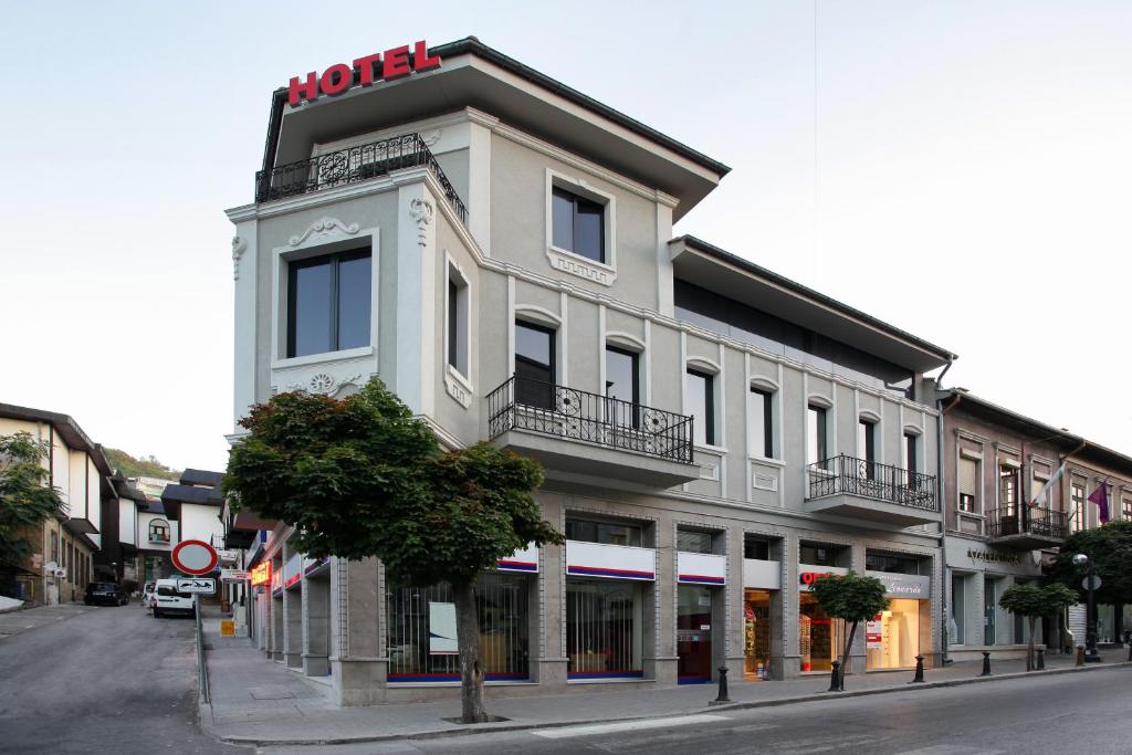 a tall white building with a hotel sign on it at Executive Rooms and Suites Play in Veliko Tŭrnovo