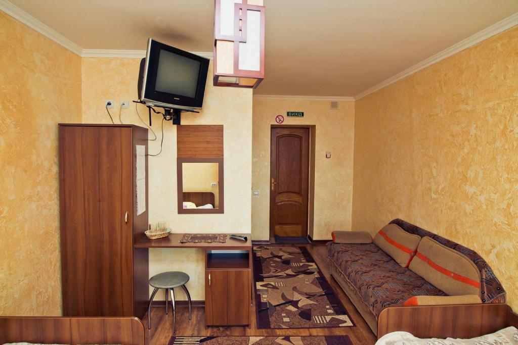 ein Wohnzimmer mit einem Sofa und einem Flachbild-TV in der Unterkunft Filvarok Hotel in Brody