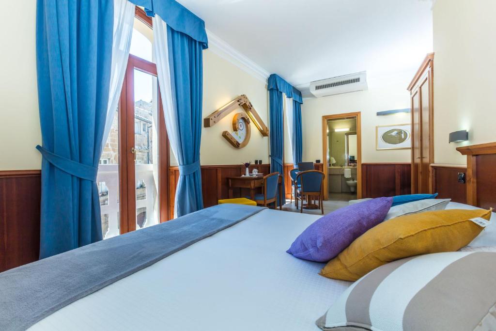 a bedroom with a large bed with blue curtains at Hotel Duomo in Orvieto