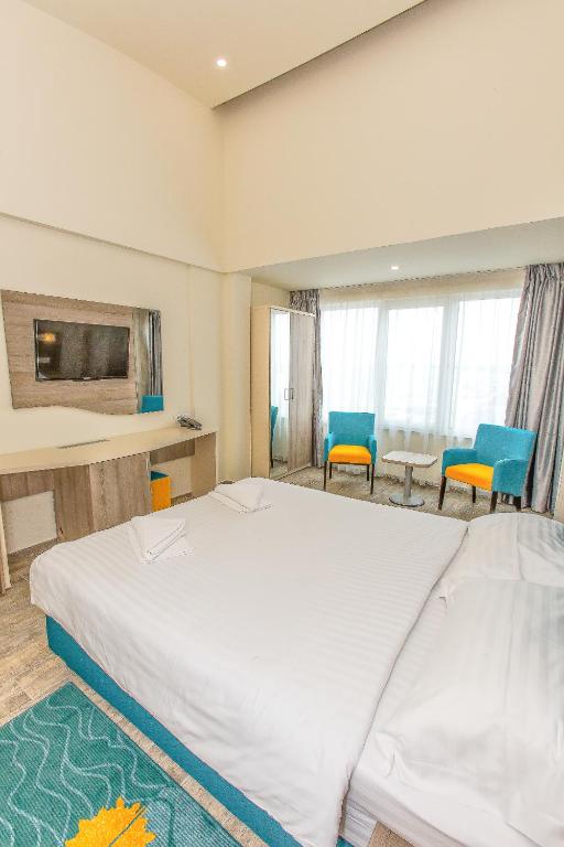 a bedroom with a large white bed and blue chairs at Hotel Riviera in Mamaia